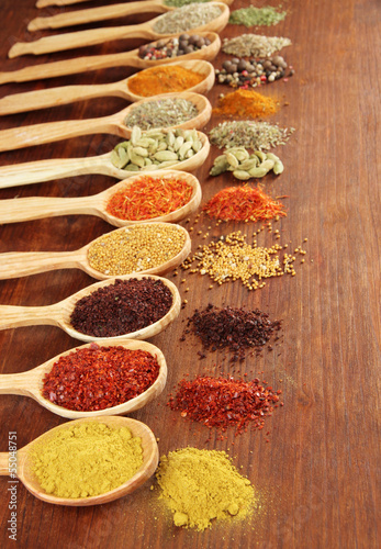 Photo: Assortment of spices in wooden spoons on wooden background Assortment of spices in wooden spoons on wooden background