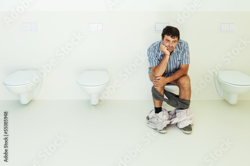 Photo: Man sitting on the toilet, public bathroom Man sitting on the toilet, public bathroom