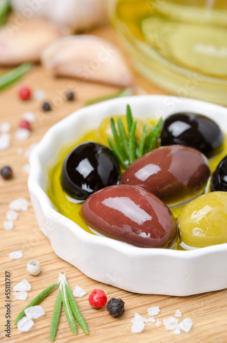 Photo: close-up of a bowl with olives in olive oil and spices on a wood close-up of a bowl with olives in olive oil and spices on a wood