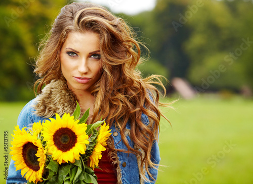 Photo: Young fashion woman with a bouquet of sunflowers in the field Young fashion woman with a bouquet of sunflowers in the field