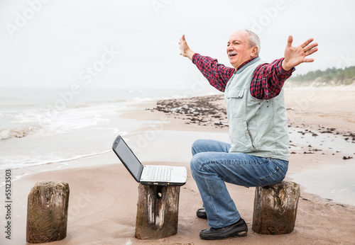 Photo: Old man with notebook on beach Old man with notebook on beach
