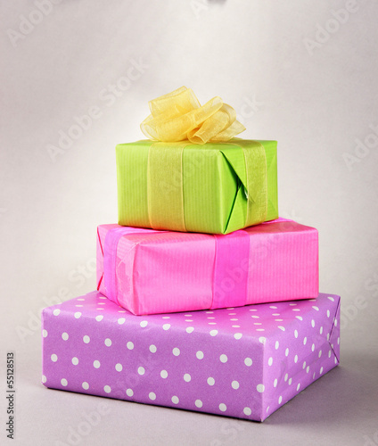 Photo: Bright gifts with bows on grey background Bright gifts with bows on grey background