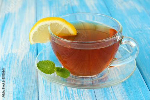 Photo: Cup of tea with lemon on table on blue background Cup of tea with lemon on table on blue background