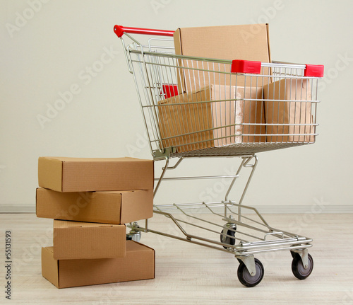 Photo: Shopping cart with carton, on gray background Shopping cart with carton, on gray background