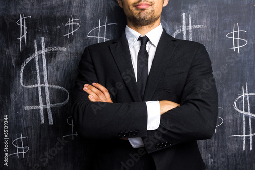 Photo: Successful businessman posing in front of dollar signs Successful businessman posing in front of dollar signs