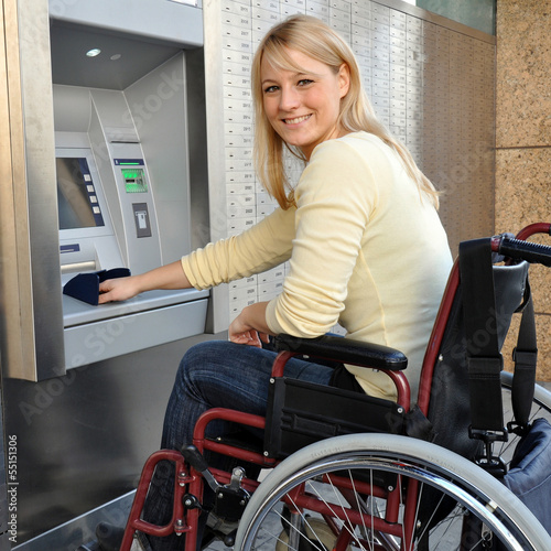 Photo: Frau im Rollstuhl bedient Geldautomaten Frau im Rollstuhl bedient Geldautomaten