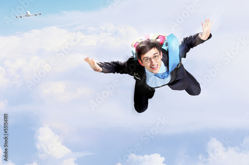 Photo: Young businessman flying with parachute on back Young businessman flying with parachute on back