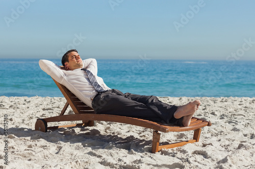 Photo: Young businessman relaxing on a deck chair Young businessman relaxing on a deck chair