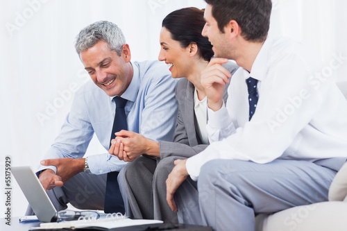 Photo: Cheerful business people working with their laptop on sofa Cheerful business people working with their laptop on sofa