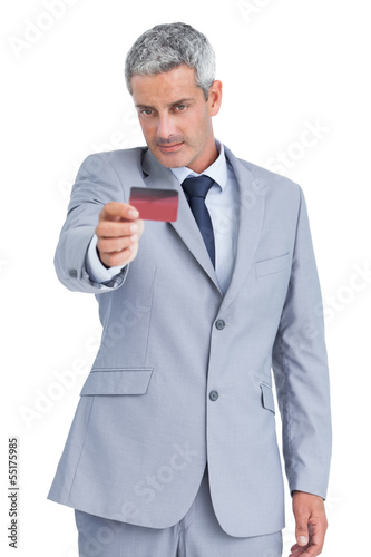 Photo: Handsome businessman holding and looking at credit card Handsome businessman holding and looking at credit card