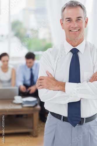 Photo: Executive standing on foreground with colleagues on background Executive standing on foreground with colleagues on background