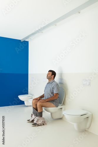 Photo: Man sitting on the toilet, public bathroom Man sitting on the toilet, public bathroom