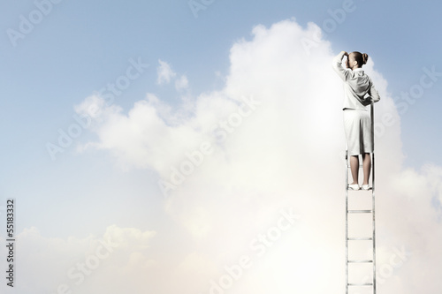 Photo: Businesswoman standing on ladder Businesswoman standing on ladder