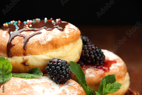 Photo: Tasty donuts with chocolate and berries on wooden table Tasty donuts with chocolate and berries on wooden table