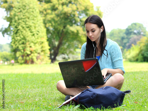 Photo: college student sitting on the grass working on laptop at campus college student sitting on the grass working on laptop at campus