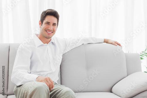 Photo: Stylish young man sitting on sofa Stylish young man sitting on sofa