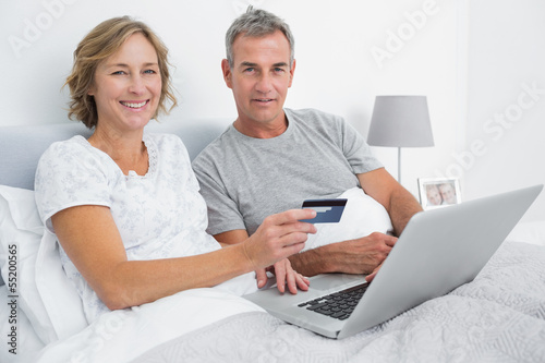 Photo: Smiling couple using their laptop to buy online Smiling couple using their laptop to buy online