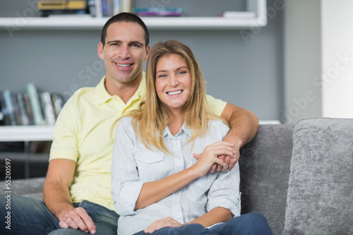 Photo: Smiling young couple sitting on their couch Smiling young couple sitting on their couch