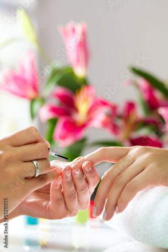 Photo: Woman in nail salon receiving manicure Woman in nail salon receiving manicure