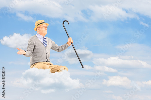 Photo: Senior man floating on a cloud and spreading arms against cloudy Senior man floating on a cloud and spreading arms against cloudy