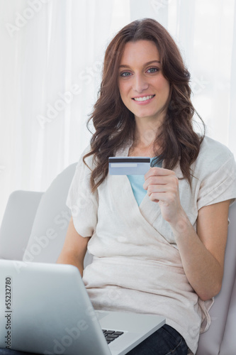 Photo: Pretty woman shopping online and smiling at camera Pretty woman shopping online and smiling at camera