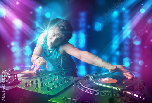 Photo: Dj mixing music in a club with blue and purple lights Dj mixing music in a club with blue and purple lights