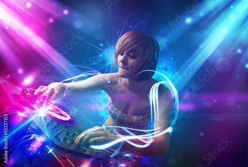 Photo: Energetic Dj girl mixing music with powerful light effects Energetic Dj girl mixing music with powerful light effects