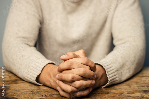 Photo: Man with folded hands seated at desk Man with folded hands seated at desk