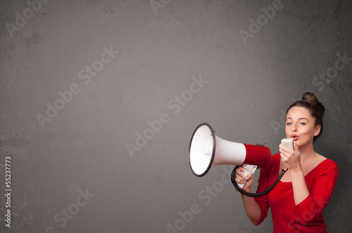 Photo: Girl shouting into megaphone on copy space background Girl shouting into megaphone on copy space background