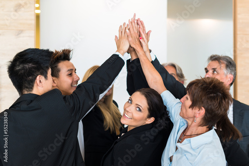 Photo: Teamwork - business people with joint hands in the office Teamwork - business people with joint hands in the office