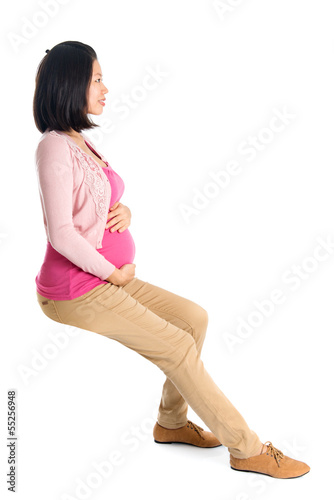 Photo: Side view pregnant Asian woman sitting Side view pregnant Asian woman sitting