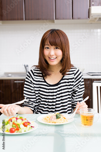 Photo: beautiful asian woman eating in the kitchen beautiful asian woman eating in the kitchen