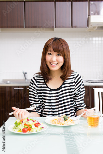 Photo: beautiful asian woman eating in the kitchen beautiful asian woman eating in the kitchen