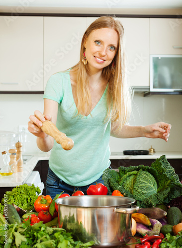 Photo: positive woman adding spices or salt to the pot positive woman adding spices or salt to the pot