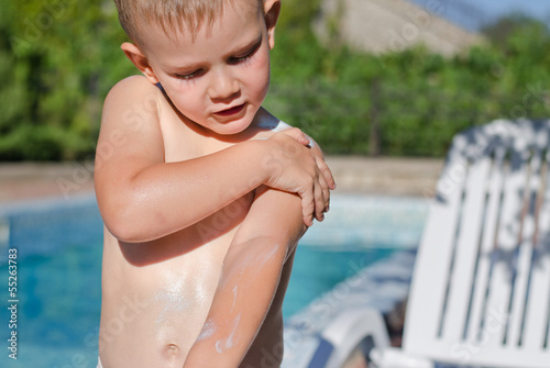 Photo: Young boy carefully applying sunscreen Young boy carefully applying sunscreen