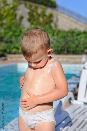 Photo: Little boy rubbing sunscreen onto his skin Little boy rubbing sunscreen onto his skin