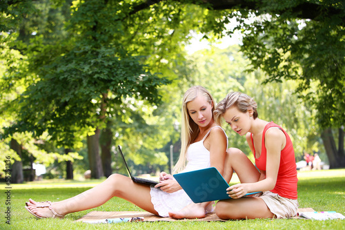 Photo: Beautiful girls using laptops at a park Beautiful girls using laptops at a park