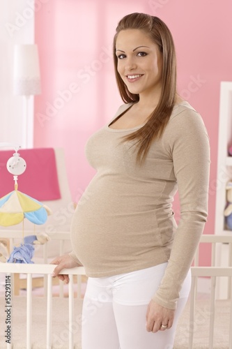 Photo: Happy pregnant mother in baby's room Happy pregnant mother in baby's room