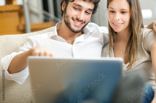 Photo: Young couple with their laptop on the couch Young couple with their laptop on the couch