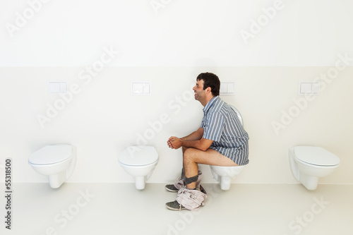 Photo: Man sitting on the toilet, public bathroom Man sitting on the toilet, public bathroom