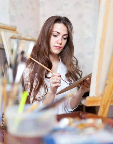 Photo: Long-haired artist paints on canvas Long-haired artist paints on canvas