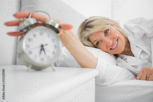 Photo: Blonde woman turning off ringing alarm clock Blonde woman turning off ringing alarm clock