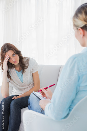 Photo: Worried woman sitting with therapist taking notes Worried woman sitting with therapist taking notes