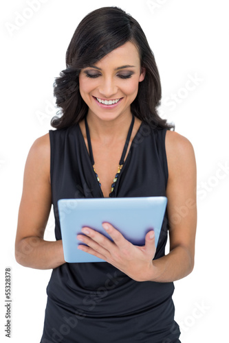 Photo: Smiling elegant brown haired model typing on tablet Smiling elegant brown haired model typing on tablet