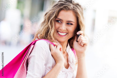 Photo: Woman talking on mobile phone and holding shopping bags Woman talking on mobile phone and holding shopping bags