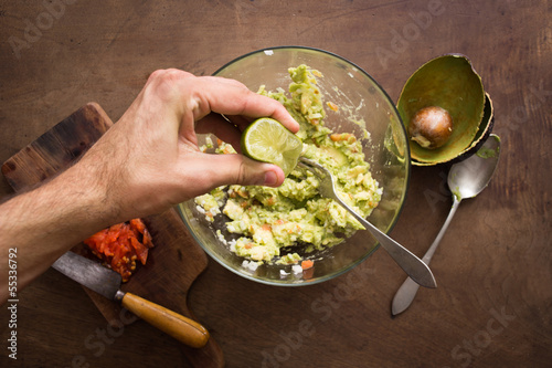 Photo: Squeezing lime on guacamole mix Squeezing lime on guacamole mix