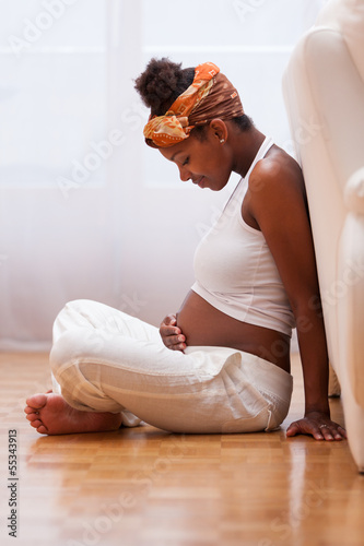 Photo: Young pregnant black woman touching her belly - African people Young pregnant black woman touching her belly - African people