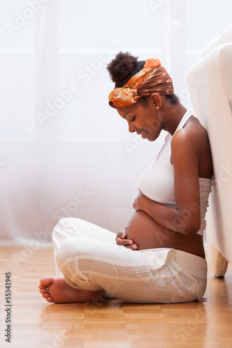 Photo: Young pregnant black woman touching her belly - African people Young pregnant black woman touching her belly - African people