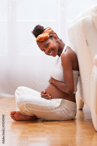 Photo: Young pregnant black woman touching her belly - African people Young pregnant black woman touching her belly - African people