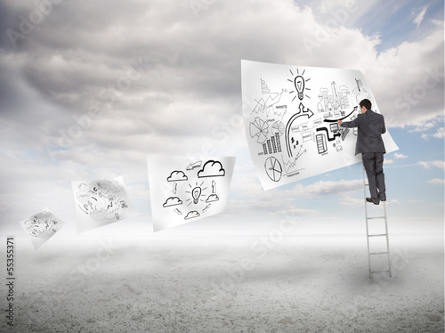 Photo: Businessman on a ladder drawing on a floating paper Businessman on a ladder drawing on a floating paper